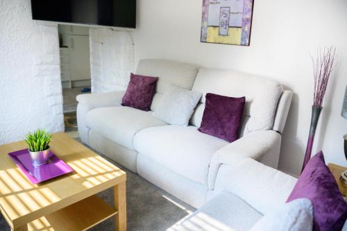 a living room with a white couch and purple pillows at Purple Blossom, cosy 2 bed apartment, near Didsbury, free parking in Manchester