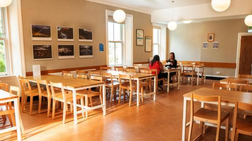 two women sitting at tables in a restaurant at Cairngorm Lodge Youth Hostel in Loch Morlich