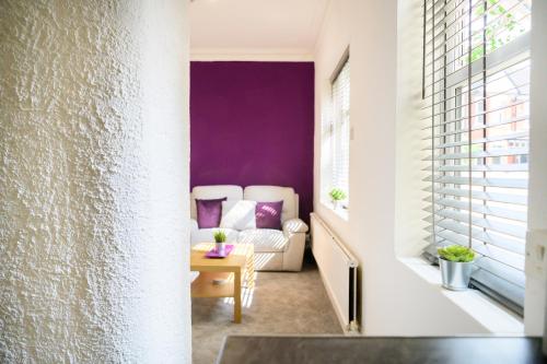 a living room with purple walls and a couch at Purple Blossom, 2 bed apartment, Wi-Fi, near Didsbury, free parking in Manchester