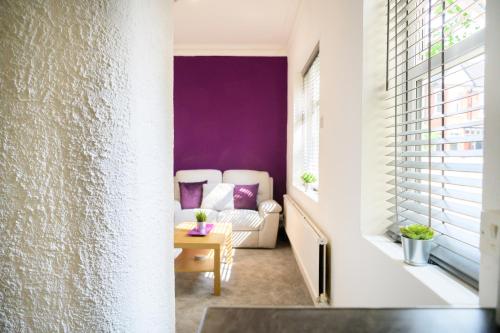 a living room with purple walls and a couch at Purple Blossom, cosy 2 bed apartment, near Didsbury, free parking in Manchester