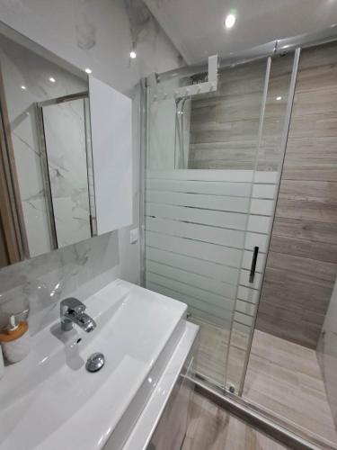 a white bathroom with a sink and a shower at Elegance apartment in Paleo Tsifliki