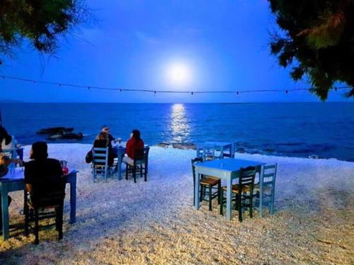 a group of people sitting at tables on the beach at Cute tiny house in Rafina