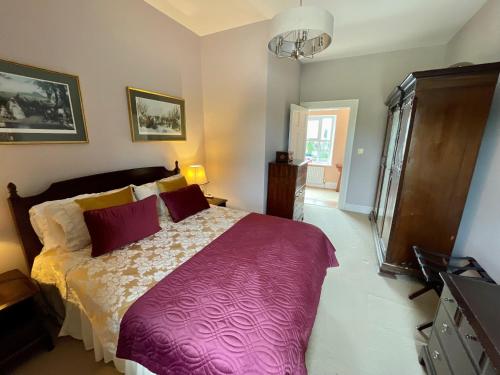 a bedroom with a large bed with a purple blanket at The Cottage at Riverbank in Ballinamallard