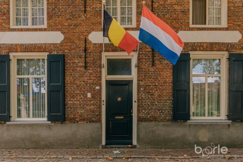 two flags on the side of a brick building at Hotel Brasserie Den Engel in Baarle-Nassau