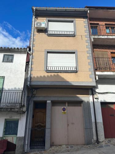 a building with two garage doors and two windows at Alojamientos Abuelo Teófilo - Valle del jerte in Tornavacas