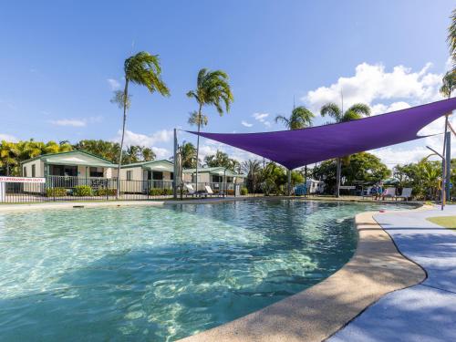 une grande piscine avec un auvent violet au-dessus de celle-ci dans l'établissement NRMA Bowen Beachfront Holiday Park, à Bowen