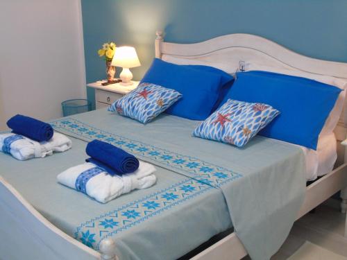 - une chambre avec un lit doté de draps et d'oreillers bleus dans l'établissement Affittacamere LiKele, à Castelsardo