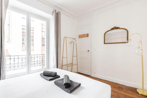 a white bedroom with a bed and a window at Apartment next Tour Montparnasse - Sable in Paris