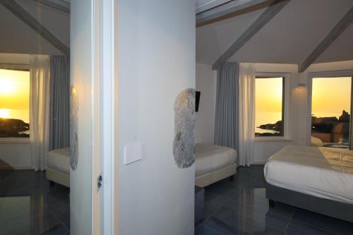 a bedroom with two beds and two windows at Oldwell Hotel in Santa Domenica
