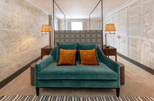 a green couch with two orange pillows in a room at The City of London Club in London