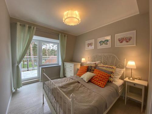 a bedroom with a bed with orange pillows and a window at Apartamenty Silence Blue Baltic in Pobierowo