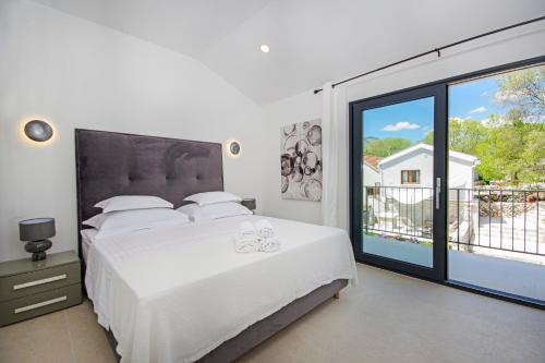 een slaapkamer met een wit bed en een groot raam bij Villa Sokol with tennis court, heating pool, gym and sauna in Sokoli