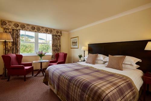 Habitación de hotel con cama, 2 sillas y ventana en Macdonald Cardrona Hotel, Golf & Spa, en Peebles