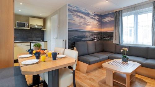 a living room with a table and a dining room at Molecaten Park Wijde Blick in Renesse
