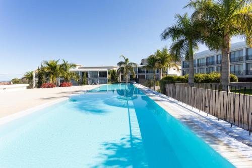 a large swimming pool with palm trees and a building at Home2Book Cozy Apt Santa Úrsula, Sea Views & Pool in Santa Úrsula