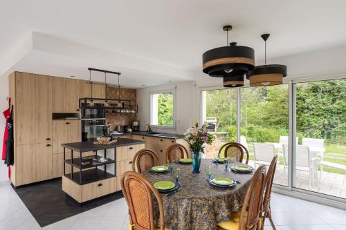 une cuisine avec une table et des chaises et une cuisine avec des fenêtres dans l'établissement Le clos de la Roche Angevin - Charmante maison 6 voyageurs, à Cancale