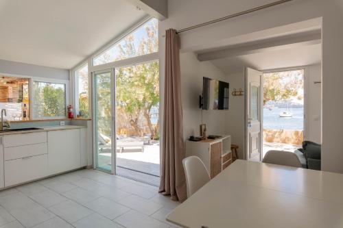 une cuisine avec une table et une grande fenêtre dans l'établissement Mon Rêve, charmant cabanon les pieds dans l'eau à la Madrague, confortable et lumineux, à Hyères