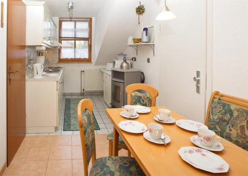 una cocina con mesa de madera y sillas con tazas y platillos en An der Seeve, Ferienhaus, en Jesteburg