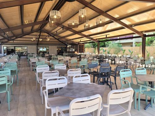 uma sala de jantar com mesas, cadeiras e lustres em Ohtels Mazagon em Mazagón