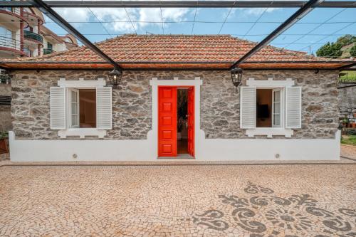 uma casa de tijolos com uma porta vermelha e janelas em Madeira Loft II - FREE CAR no Caniço