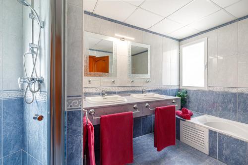a bathroom with two sinks and a tub and red towels at Altea Buena Vista in Altea