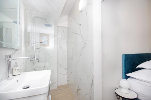 een witte badkamer met een wastafel en een douche bij Villa Sokol with tennis court, heating pool, gym and sauna in Sokoli