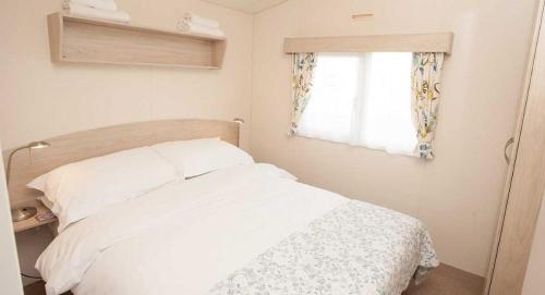 1 dormitorio con cama blanca y ventana en The Hide near Aviemore en Aviemore