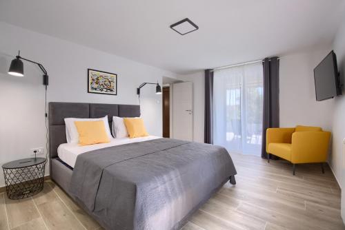 a bedroom with a large bed and a yellow chair at Apartment Marin 2 near the beach in Banjole