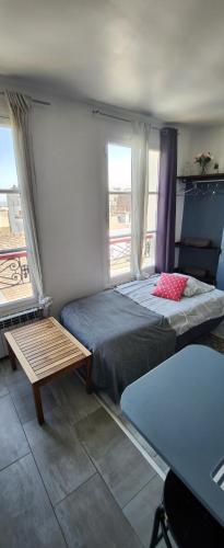 una camera con un letto e un tavolo e due finestre di The heart of Montmartre a Parigi