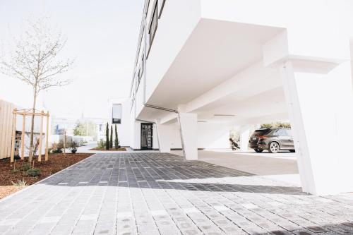 a white building with a car parked in a parking lot at Boardinghouse Plattling in Plattling