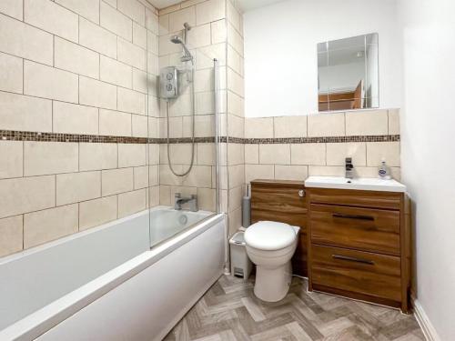 ein Badezimmer mit einer Badewanne, einem WC und einem Waschbecken in der Unterkunft Coronation Mill Apartment in Mow Cop