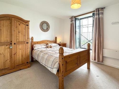 ein Schlafzimmer mit einem Holzbett und einem großen Fenster in der Unterkunft Coronation Mill Apartment in Mow Cop