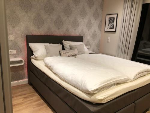 ein großes Bett mit weißer Bettwäsche und Kissen in der Unterkunft Pistenblume Apartment - Skipiste, Stadtzentrum in Winterberg