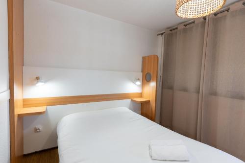 a small bedroom with a white bed and a window at Kyriad Direct Bordeaux Sud Cestas in Cestas
