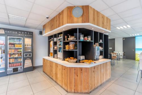 a counter in a restaurant with a clock on the wall at Kyriad Direct Bordeaux Sud Cestas in Cestas