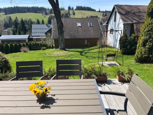a wooden table with flowers on it in a yard at Rodinné apartmány Rafael Bedřichov in Bedřichov