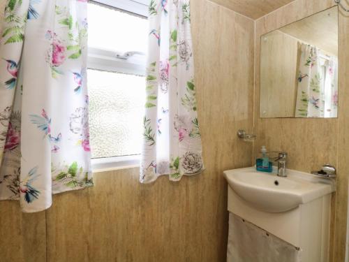 a bathroom with a sink and a window with curtains at Ardea in Norwich