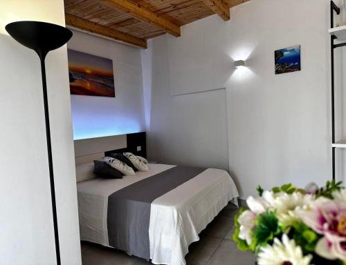 ein Schlafzimmer mit einem Bett, einer Lampe und Blumen in der Unterkunft Dimora Schiappone in Ischia