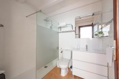a white bathroom with a toilet and a sink at Casa del Sol in Búger