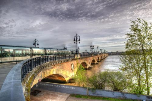 a bridge over a river with a train on it at Kyriad Direct Bordeaux Sud Cestas in Cestas