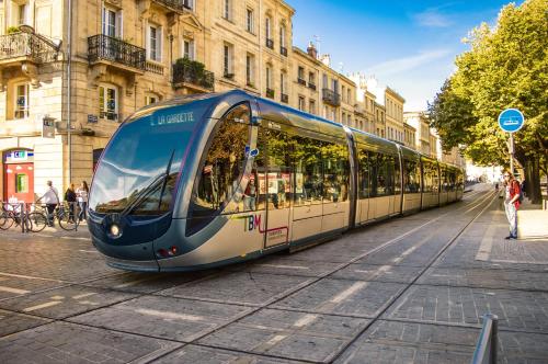 a blue and white tram on a city street at Kyriad Direct Bordeaux Sud Cestas in Cestas