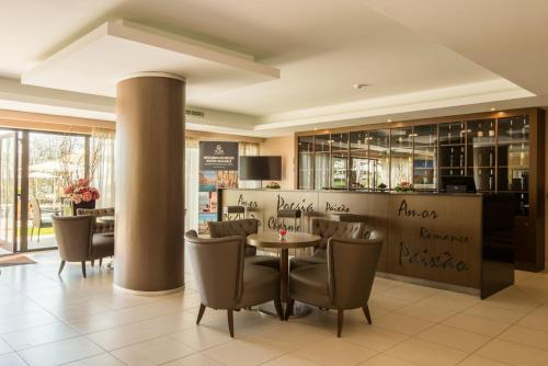 a restaurant with a table and chairs and a bar at Vila Gale Collection Palácio dos Arcos in Oeiras