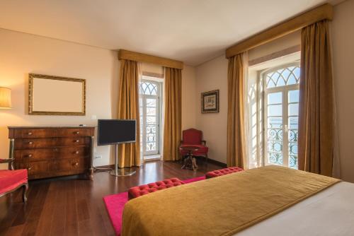 a bedroom with a bed and a flat screen tv at Vila Gale Collection Palácio dos Arcos in Oeiras