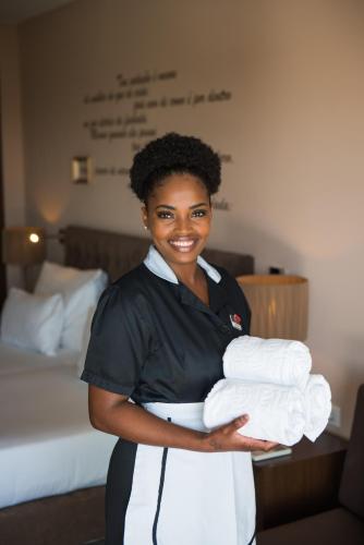 a woman is holding a pile of towels at Vila Gale Collection Palácio dos Arcos in Oeiras