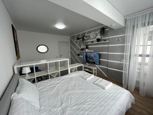 1 dormitorio con cama blanca y reloj en la pared en Perla Home - Studio 22, en Popeşti-Leordeni