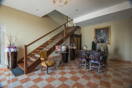a man sitting at a desk in a room with a staircase at Vila Gale Collection Palácio dos Arcos in Oeiras