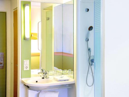 a bathroom with a sink and a shower with a mirror at Ibis budget Hamburg Quickborn in Quickborn