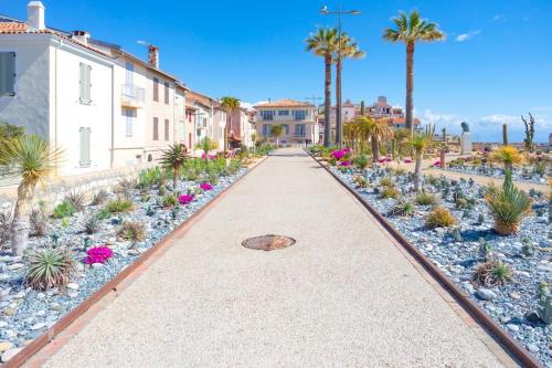 a walkway through a resort with palm trees and plants at A9 - 1 BDR Fantastic Sea View Remparts Old Antibes - AC in Antibes