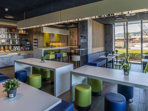 a restaurant with white tables and green stools at Ibis Budget Barcelona Viladecans in Viladecáns