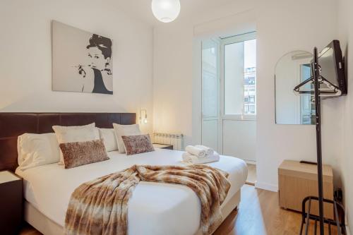 biała sypialnia z łóżkiem z kocem w obiekcie Barcelonaforrent The Gaudí Suites w Barcelonie